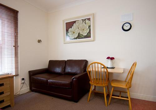 a living room with a leather couch and a table and chairs at Glencourt Apartments in Dublin