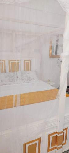 a white bedroom with two beds and a window at Neighbourly Nest in Mombasa