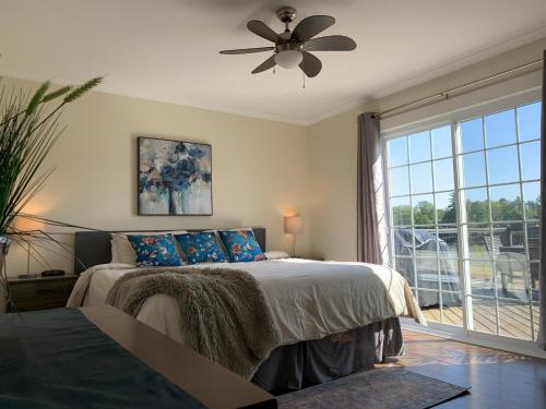 een slaapkamer met een bed, een plafondventilator en een raam bij 4 bedroom 3 bathroom Riverside Retreat with seasonal heated pool and hot tub Sleeps 12 Durham Nova Scotia in Pictou