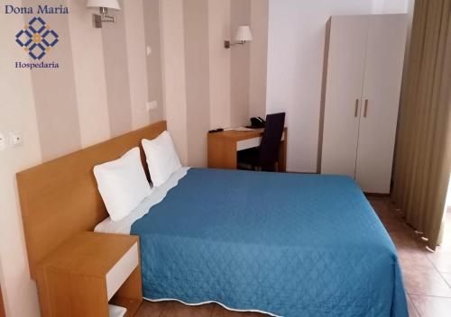 una camera da letto con un letto blu e una scrivania di Hospedaria Dona Maria a Beja