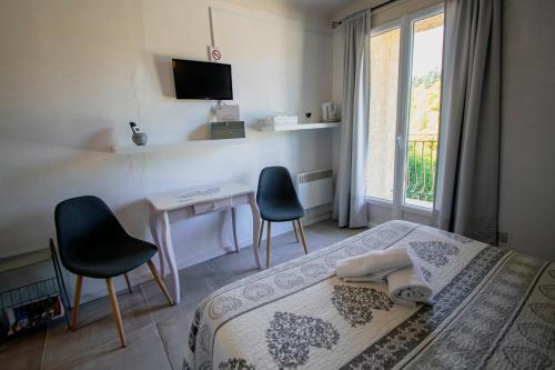 a bedroom with a bed and a desk with two chairs at Hotel Carina in Apt