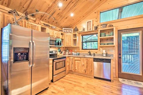 a kitchen with a stainless steel refrigerator and wooden cabinets at Broken Bow Hideaway with Hot Tub and Fire Pit! in Stephens Gap