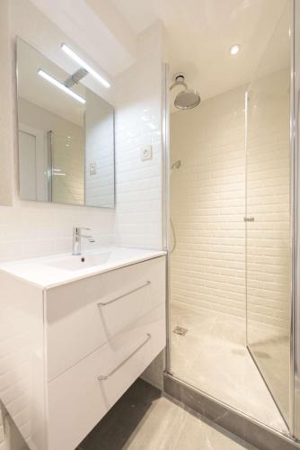 une salle de bain blanche avec un lavabo et une douche dans l'établissement Candide, à Paris
