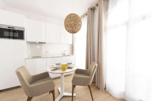 a white kitchen with a table and two chairs at Candide in Paris