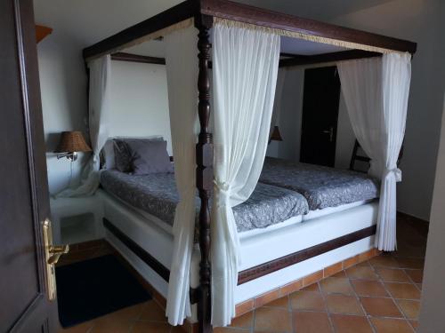 Casa Luz في إرميغوا: غرفة نوم مع سرير بأربعة أعمدة مع ستائر