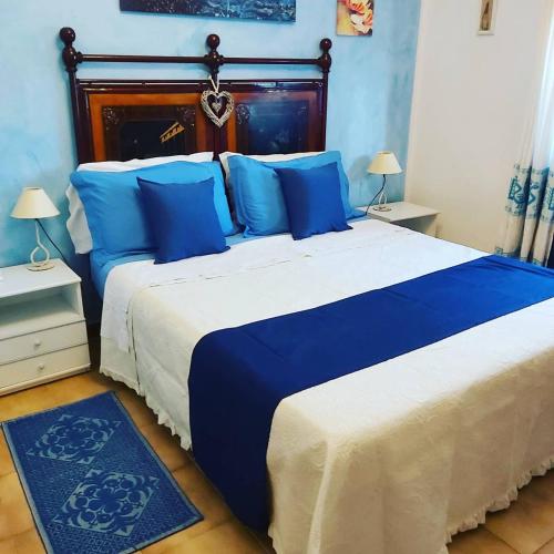 a blue and white bed with blue pillows in a bedroom at Bed & Breakfast Il Rosmarino in Bosa