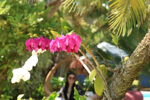 a woman standing next to a pink and white flower at Pousada Arriba Pipa in Pipa