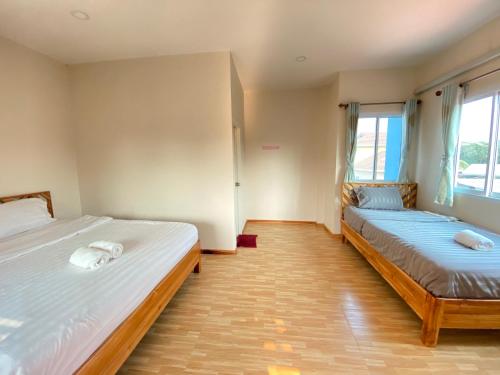 a bedroom with two beds and two windows at เชียงคาน เรสติ้ง เพลส in Chiang Khan