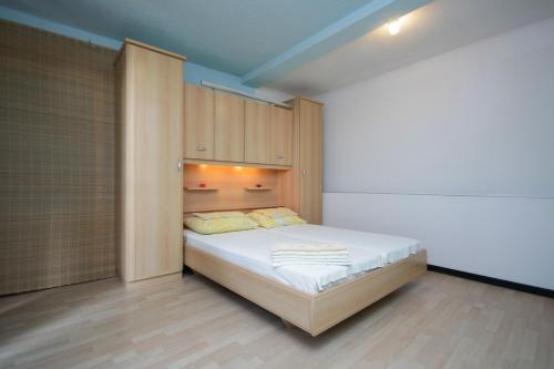 1 dormitorio con 1 cama y armarios de madera en Apartments Marić, en Primošten