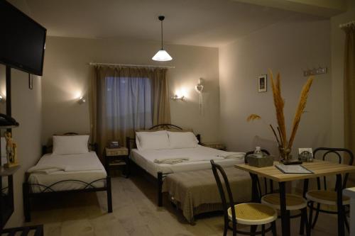Habitación de hotel con 2 camas, mesa y sillas en Thalis Rooms, en Skoutari