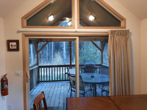 a screened in porch with a table and chairs on a deck at Willamette Pass Inn & Chalets in Odell Lake
