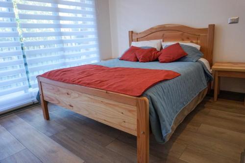 a bedroom with a wooden bed with red pillows at Ideal para parejas, 1 ambiente in Pucón