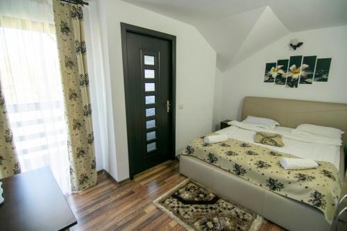 a bedroom with a bed and a table and a door at Alpina Panoramic in Moisei