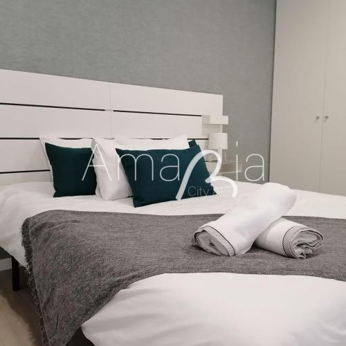 um quarto com uma grande cama branca com almofadas em AmaRiaCity AL em Aveiro