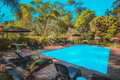 une grande piscine avec des chaises et des parasols dans l'établissement Pousada Santuário Acalanto, à São Roque