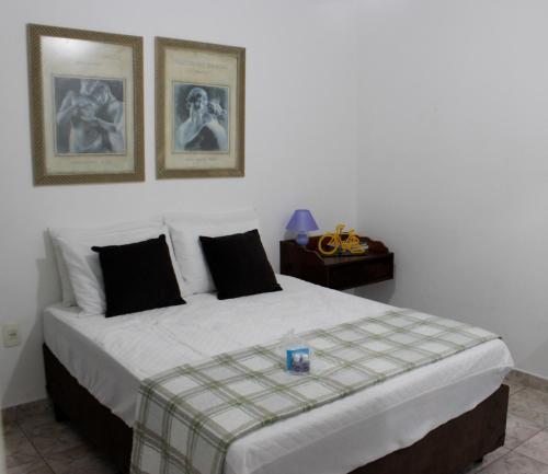 a bedroom with a large bed with two pictures on the wall at Rota 013 - Santos Canal 4 in Santos