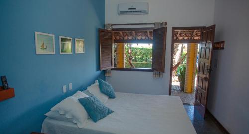 a bedroom with a bed with blue walls and a window at Pousada Canto do Rio in Prado