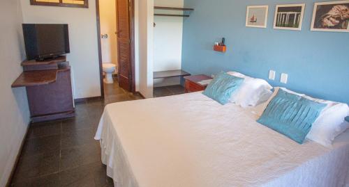 a bedroom with a white bed with two blue pillows at Pousada Canto do Rio in Prado