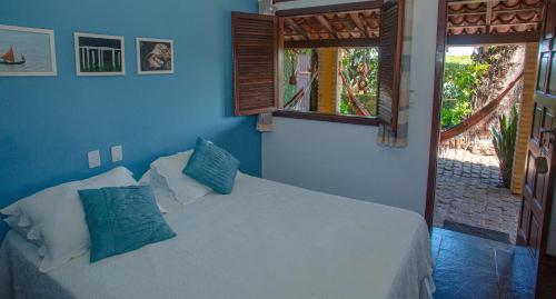 a bedroom with a bed with blue walls and a window at Pousada Canto do Rio in Prado