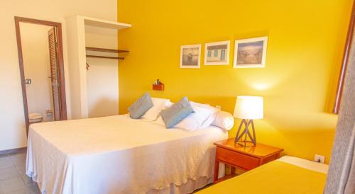 a yellow room with two beds and a lamp at Pousada Canto do Rio in Prado