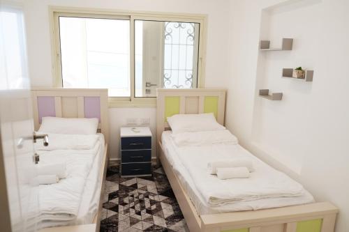 Duas camas num pequeno quarto com uma janela em SleepWell Suite em Majdal Shams