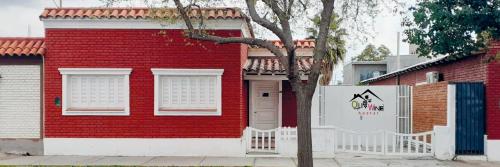 dom z czerwonej cegły z białym płotem przed nim w obiekcie OliWine hostel w mieście Maipú