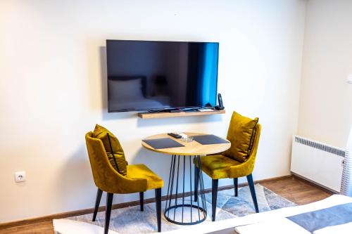 a room with a table and two chairs and a tv at Omega Apartments in Vrnjačka Banja