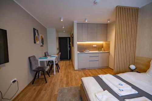 a bedroom with a bed and a table and a kitchen at Omega Apartments in Vrnjačka Banja