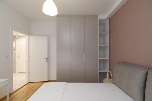 biała sypialnia z łóżkiem i szafą w obiekcie Blu & Marrone Suites-free parking w Salonikach