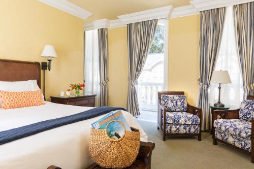 a hotel room with a bed and two chairs at West Cliff Inn, A Four Sisters Inn in Santa Cruz