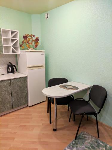 a kitchen with a table and two chairs and a refrigerator at Oasis Apartments in Pärnu