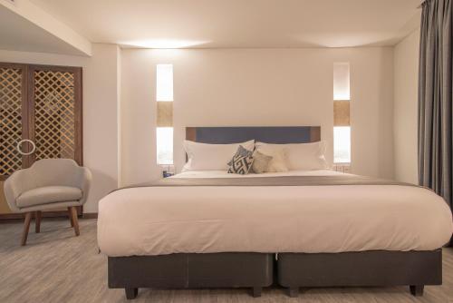 a bedroom with a large bed and a chair at Hotel Santa Catalina By OxoHotel in Cartagena de Indias