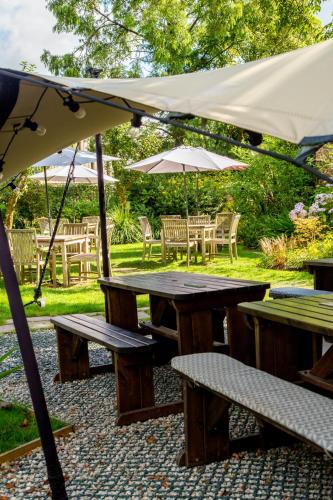 a picnic table and benches under an umbrella at Castle Inn in Lydford