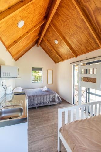 a bedroom in a house with a bed and a kitchen at Camp Waipu Cove in Waipu
