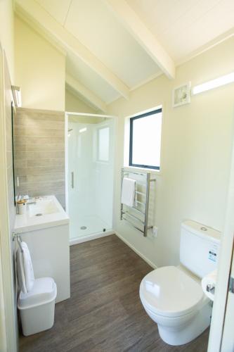 a white bathroom with a toilet and a sink at Camp Waipu Cove in Waipu