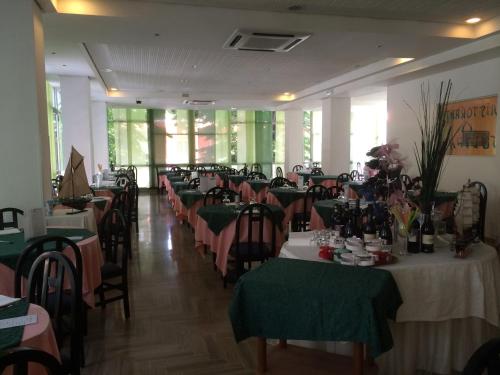 a dining room with tables with green and pink tablecloths at Hotel Sultano in Rimini