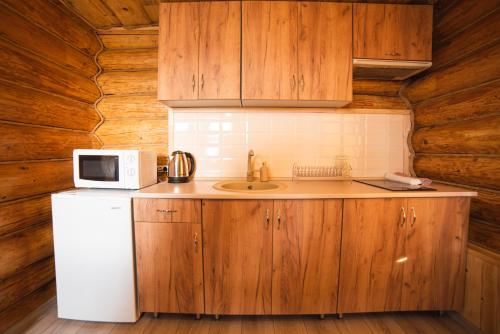a kitchen with wooden cabinets and a sink and a microwave at Hygge House in Vyshka