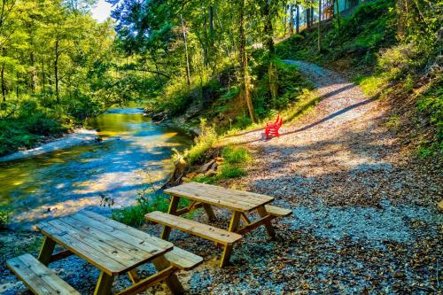 two picnic tables sitting next to a river at Talking Creek Lodge in Talking Rock