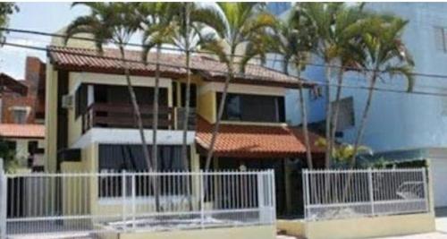 una casa con palmeras y una valla blanca en Pousada Santa Barbara, en Florianópolis