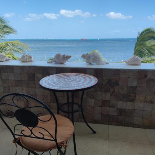 a table and chair in front of a counter with the ocean at Bella Beach Condo Cancun in Cancún