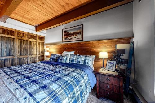 1 dormitorio con 1 cama y pared de madera en Glacier & Ducks Unlimited, en Big Sky