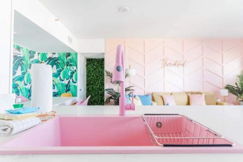 a pink kitchen with a sink and a living room at My Beach Retreat by Nick in Gulf Shores