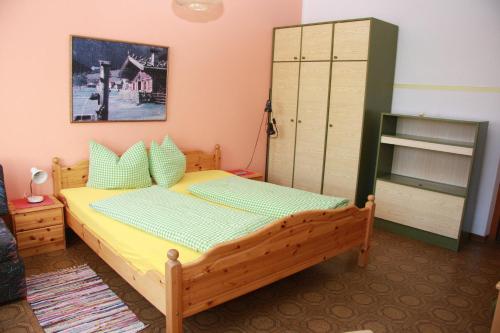 a bedroom with a wooden bed and a cabinet at Appartementhaus Sabine in Obertilliach