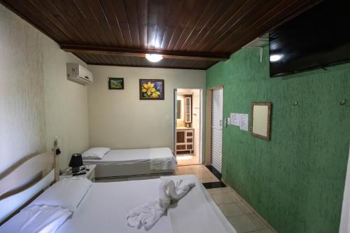 Habitación con 2 camas y pared verde. en Pousada Dalmar, en Penha