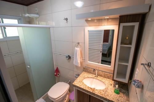 a bathroom with a sink and a toilet and a mirror at Pousada Dalmar in Penha