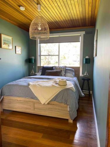 1 dormitorio con 1 cama con sombrero en Lylah’s By The Sea, en Wynyard