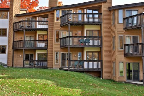 an apartment building with balconies and a yard at Okemo Mountain Lodge in Ludlow