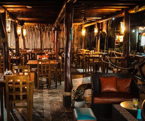 a restaurant with tables and chairs and a couch at Primaluna Beach Hostel in Palomino