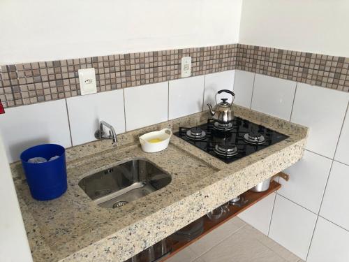 a kitchen counter with a stove and a sink at Apartamento Ilha do Coral in Palhoça