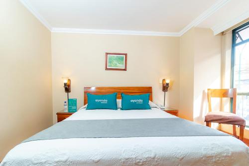 a bedroom with a large bed with blue pillows at Ayenda La Antigua in Tunja